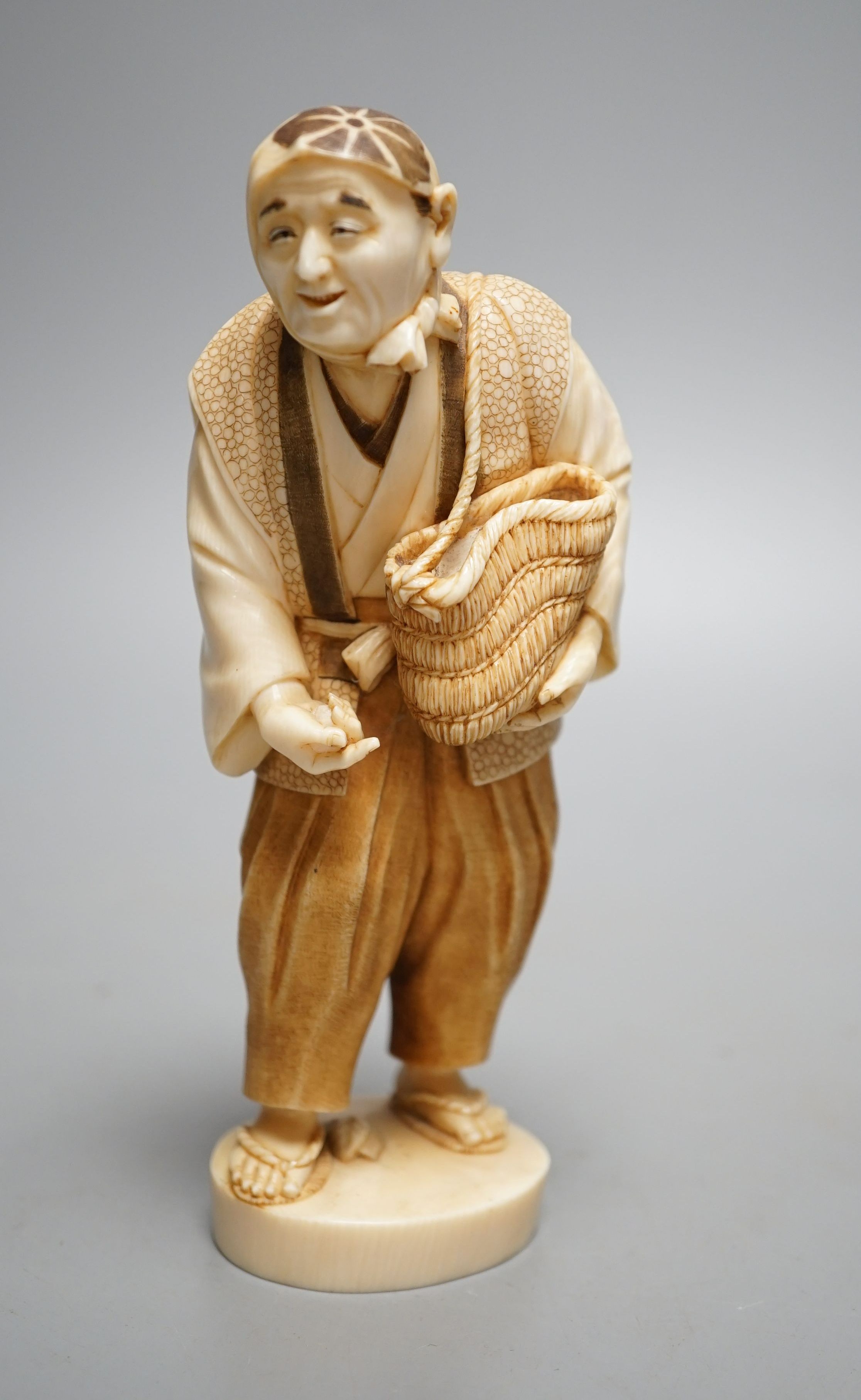 A Japanese ivory figure of a peasant farmer, Taisho/early Showa period, signed to a lacquer tablet - 17cm tall